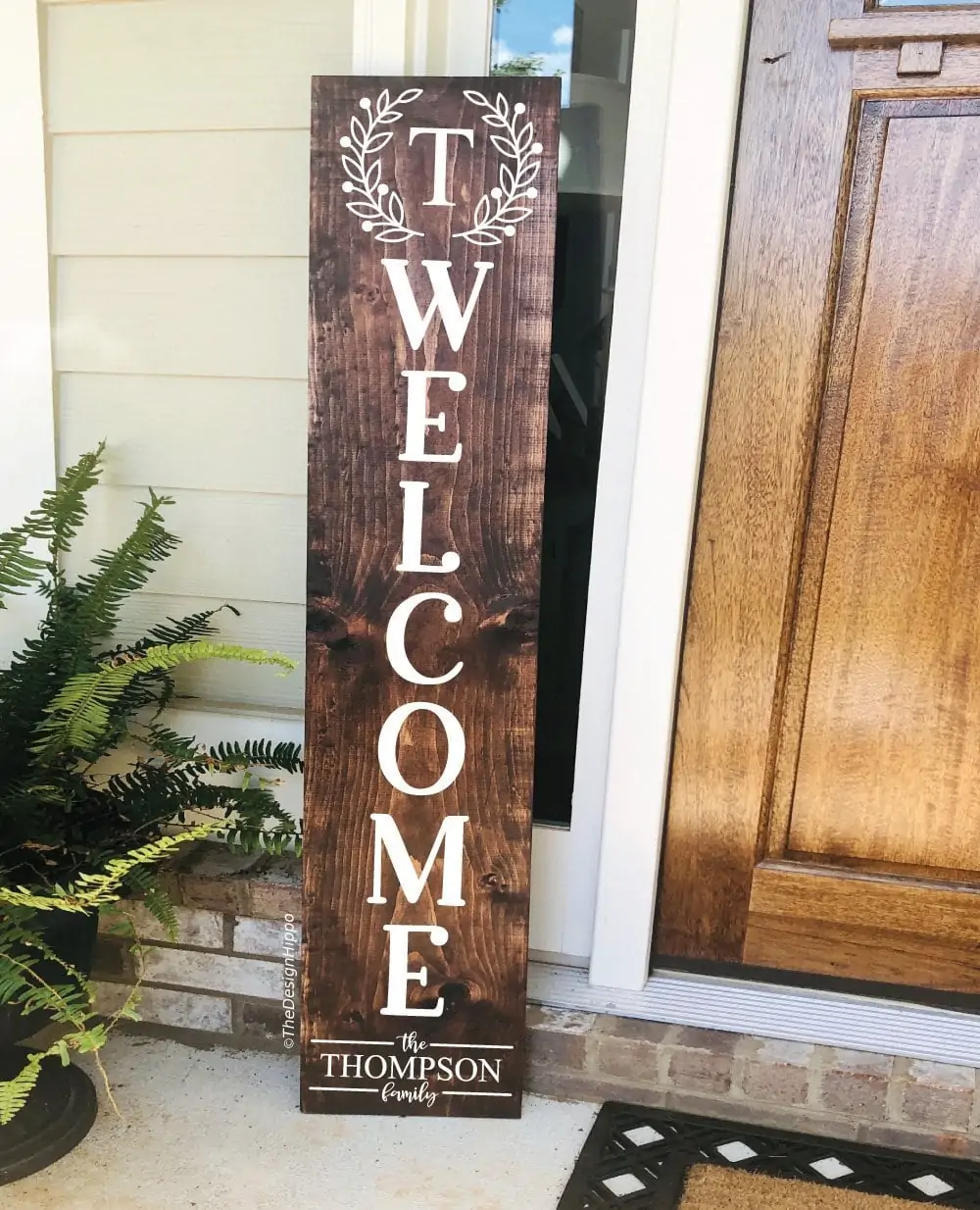 tall dark wood porch sign that says welcome with a letter T monogram and the Thompson family