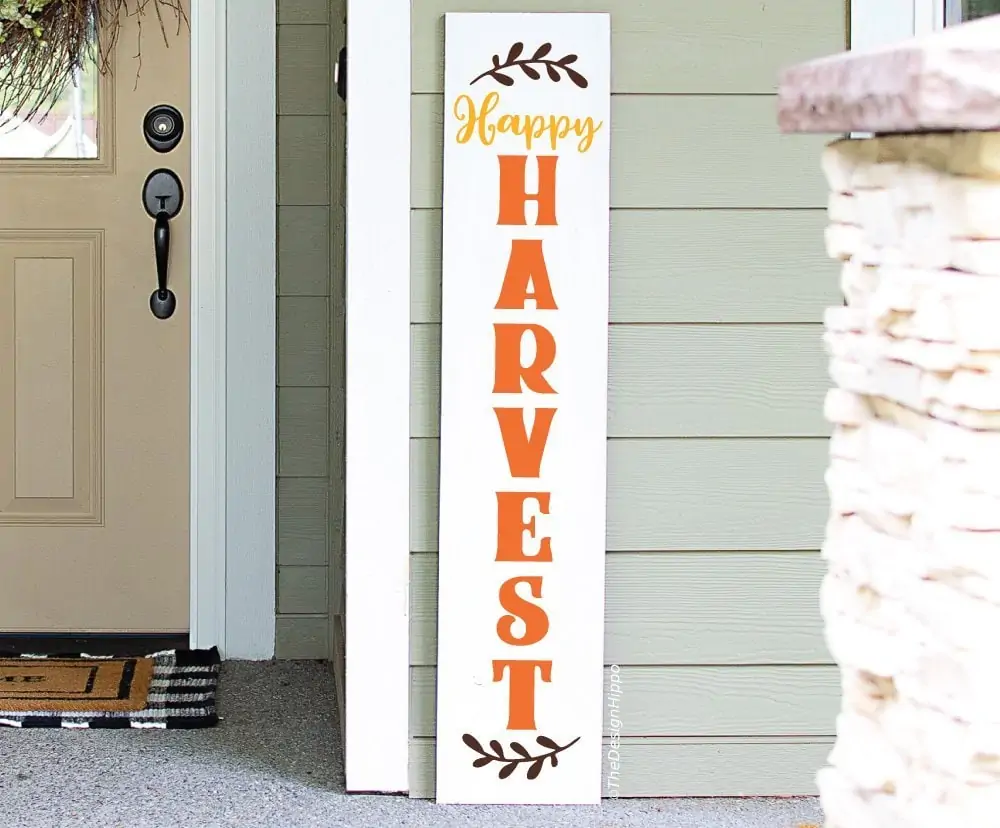 tall white Happy Harvest porch sign leaning beside a front door