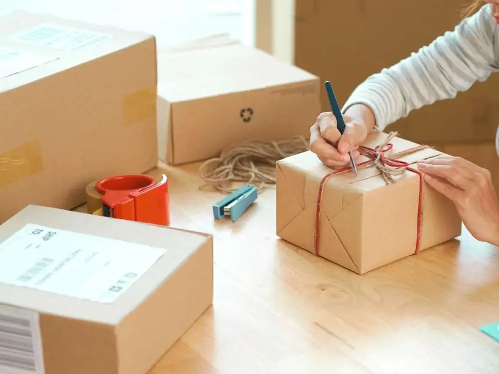 women packing a cricut project to sell on a wooden table surrounded by boxes