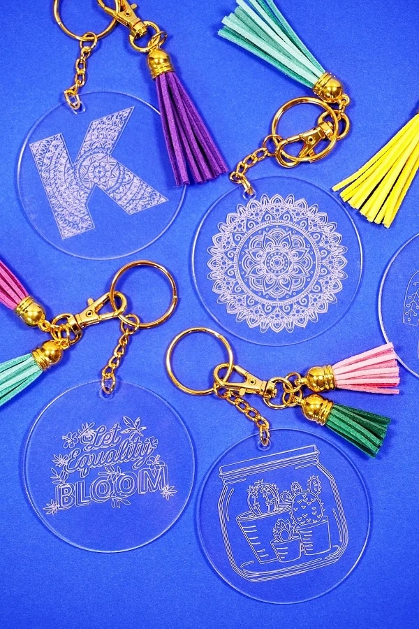 display of four custom engraved acrylic keychains made with Cricut Maker on a blue background