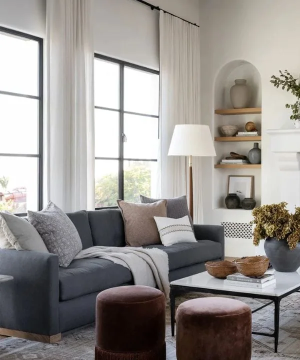 Charcoal gray sofa with white curtains and built-in alcove shelving in modern living room
