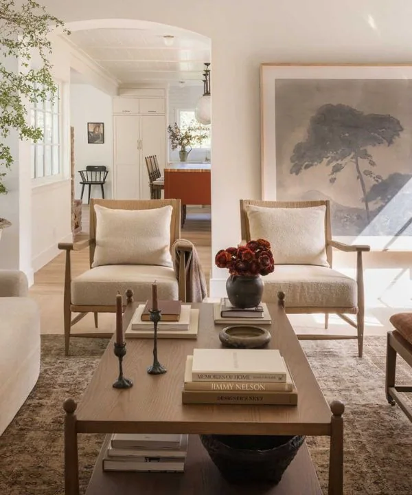 Matching cream bouclé chairs with tree artwork and styled coffee table in modern living room