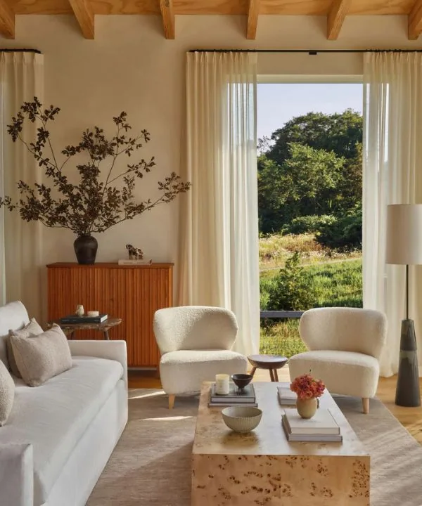 Light-filled living room with cream bouclé chairs, white sofa, and burl wood coffee table