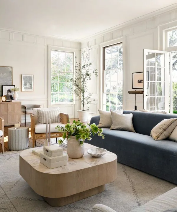 Modern living room with large artwork, neutral cane chair, and blue-gray sofa with built-in shelving