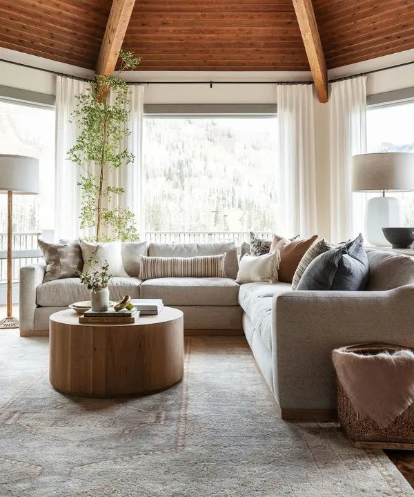 Modern living room with mountain views through floor-to-ceiling windows and neutral sectional
