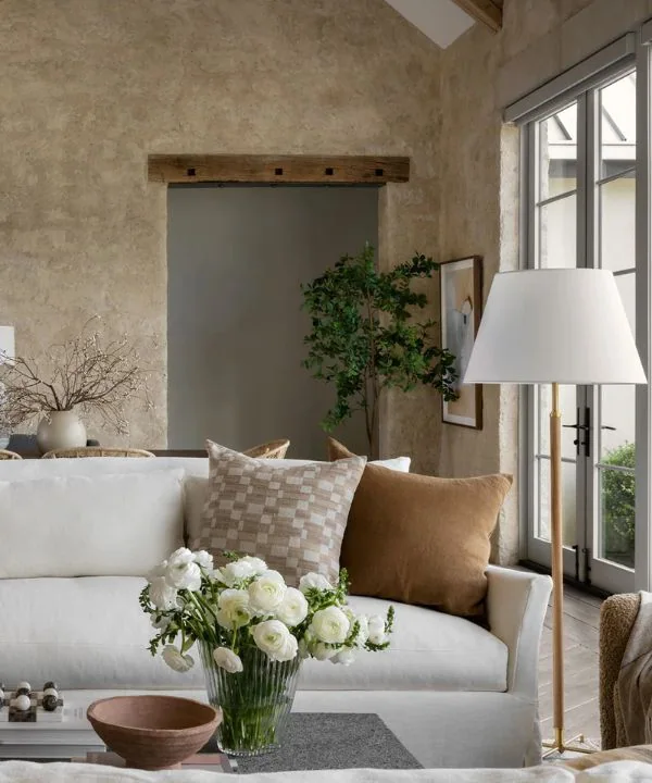 White sofa against textured plaster walls with wooden beams and fresh white flowers