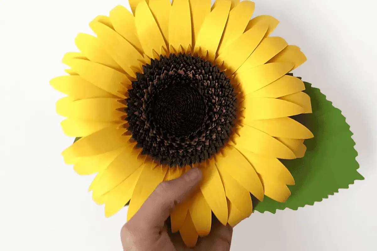 large yellow 3D paper sunflower with a brown center and a green leaf