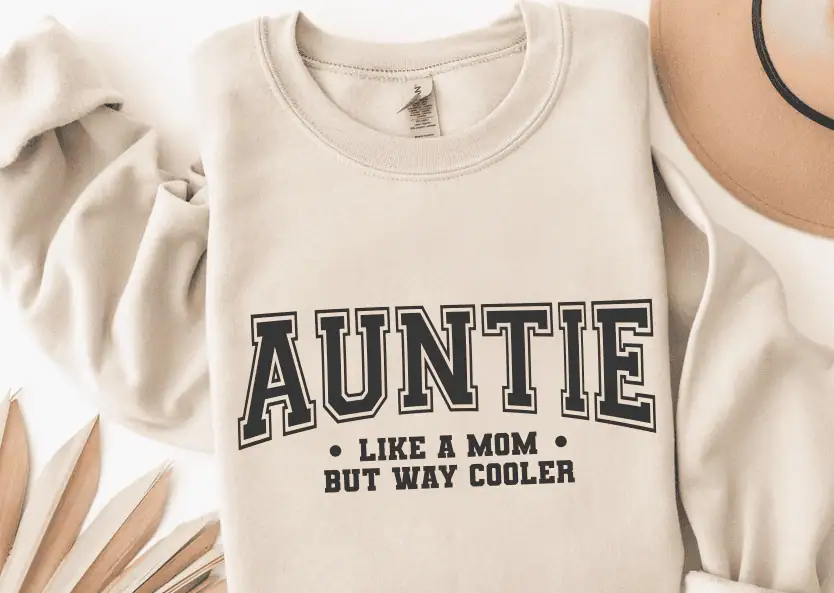 cream sweatshirt that says Auntie, like a mom but way cooler in varsity letters