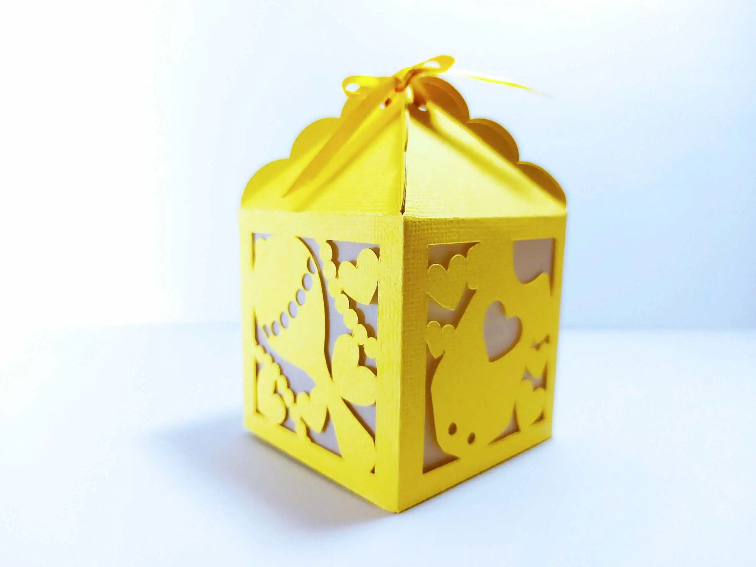 yellow paper favor box with heart cutouts and a ribbon tied at the top