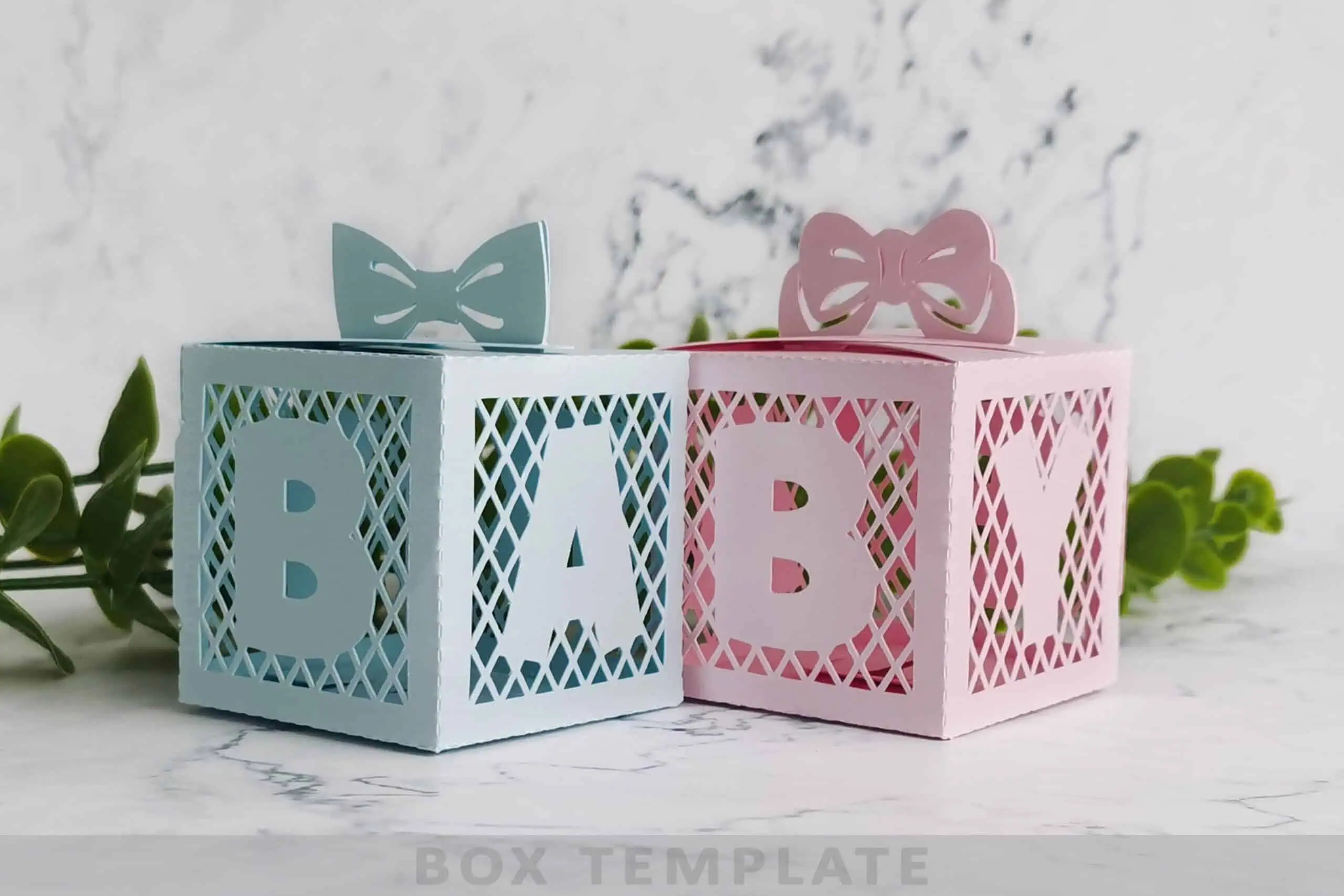 pastel blue and pink paper favor boxes with lattice cutouts spelling BABY, with bows on top