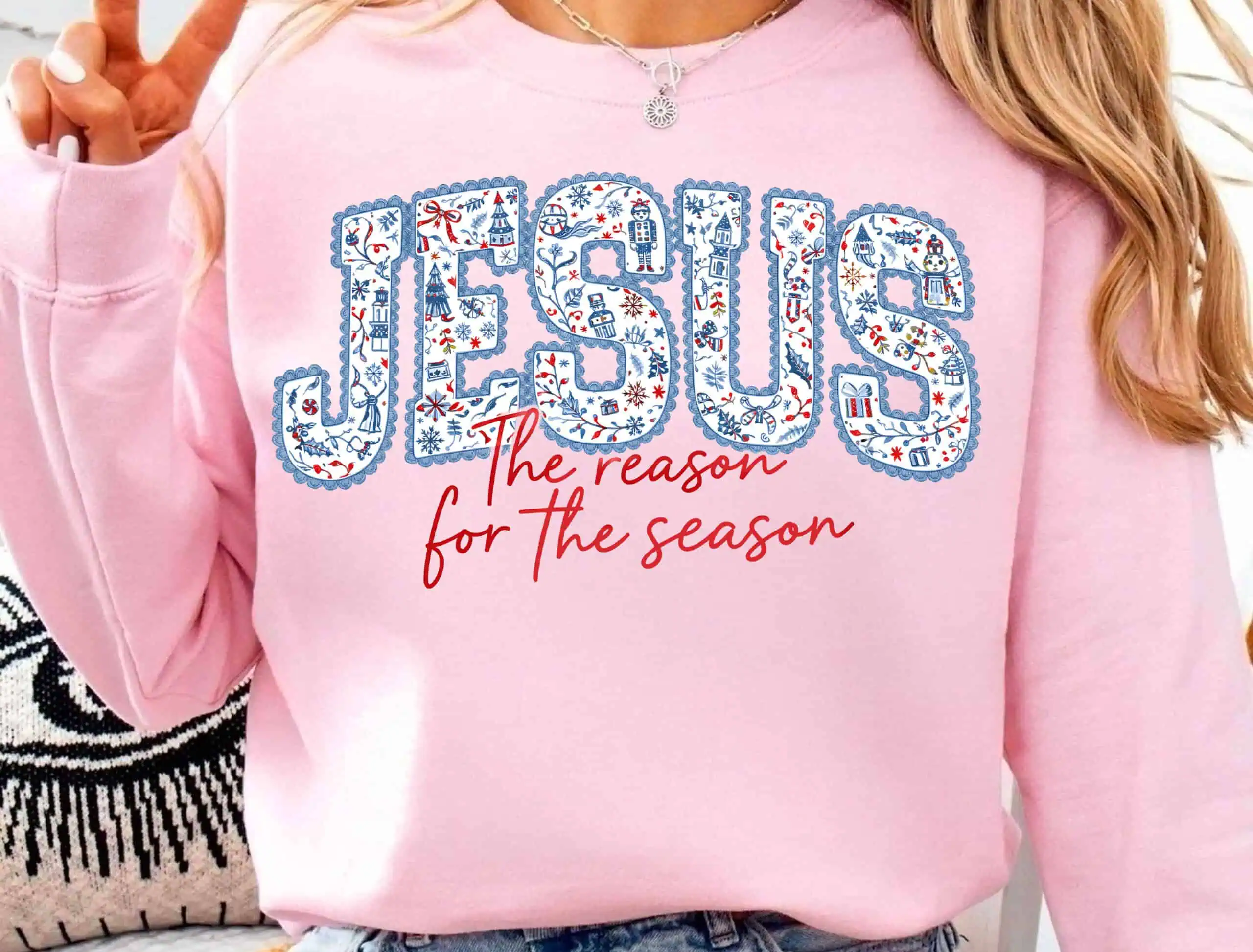 pink sweatshirt that says Jesus in blue floral faux embroidery letters with the reason for the season in script