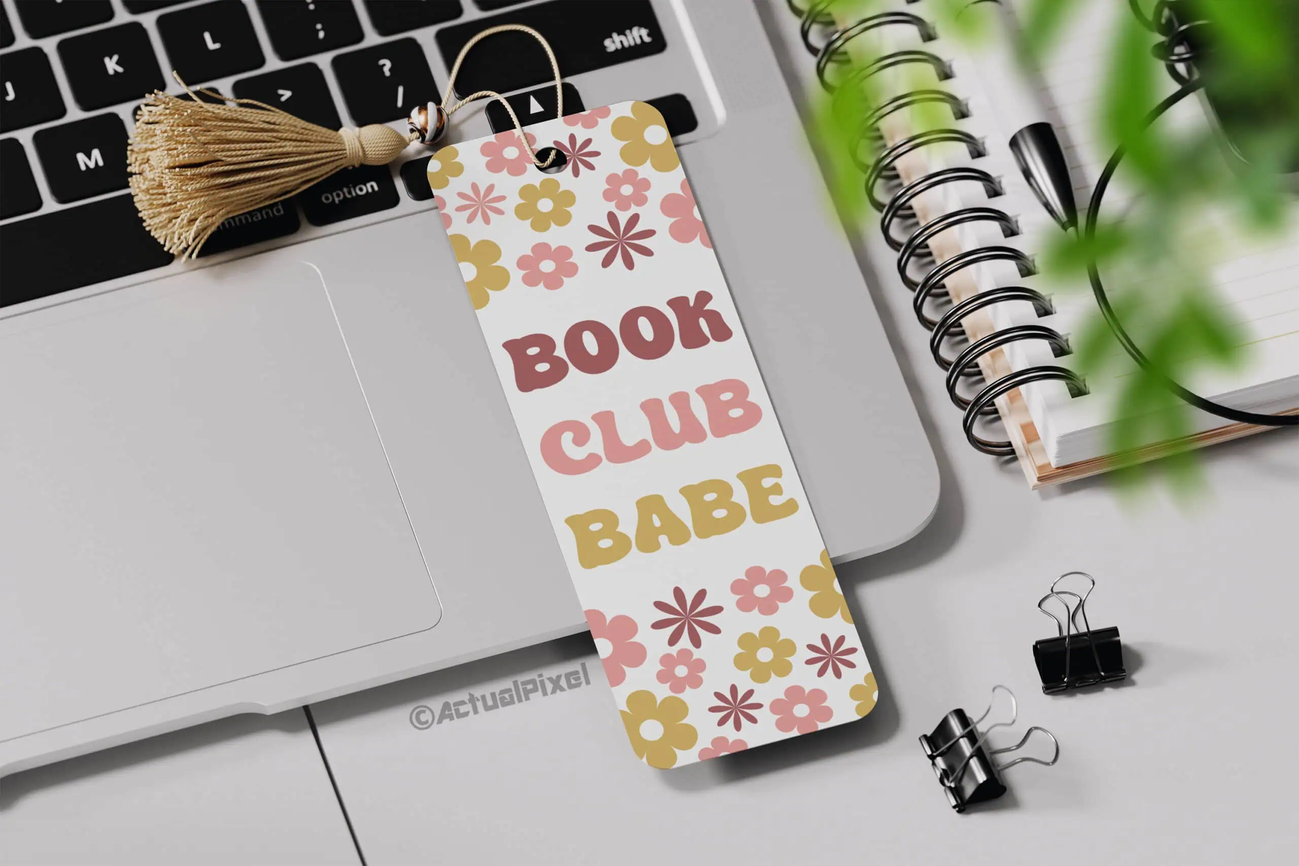 bookmark that says book club babe with retro flowers and a jute tassel next to a laptop
