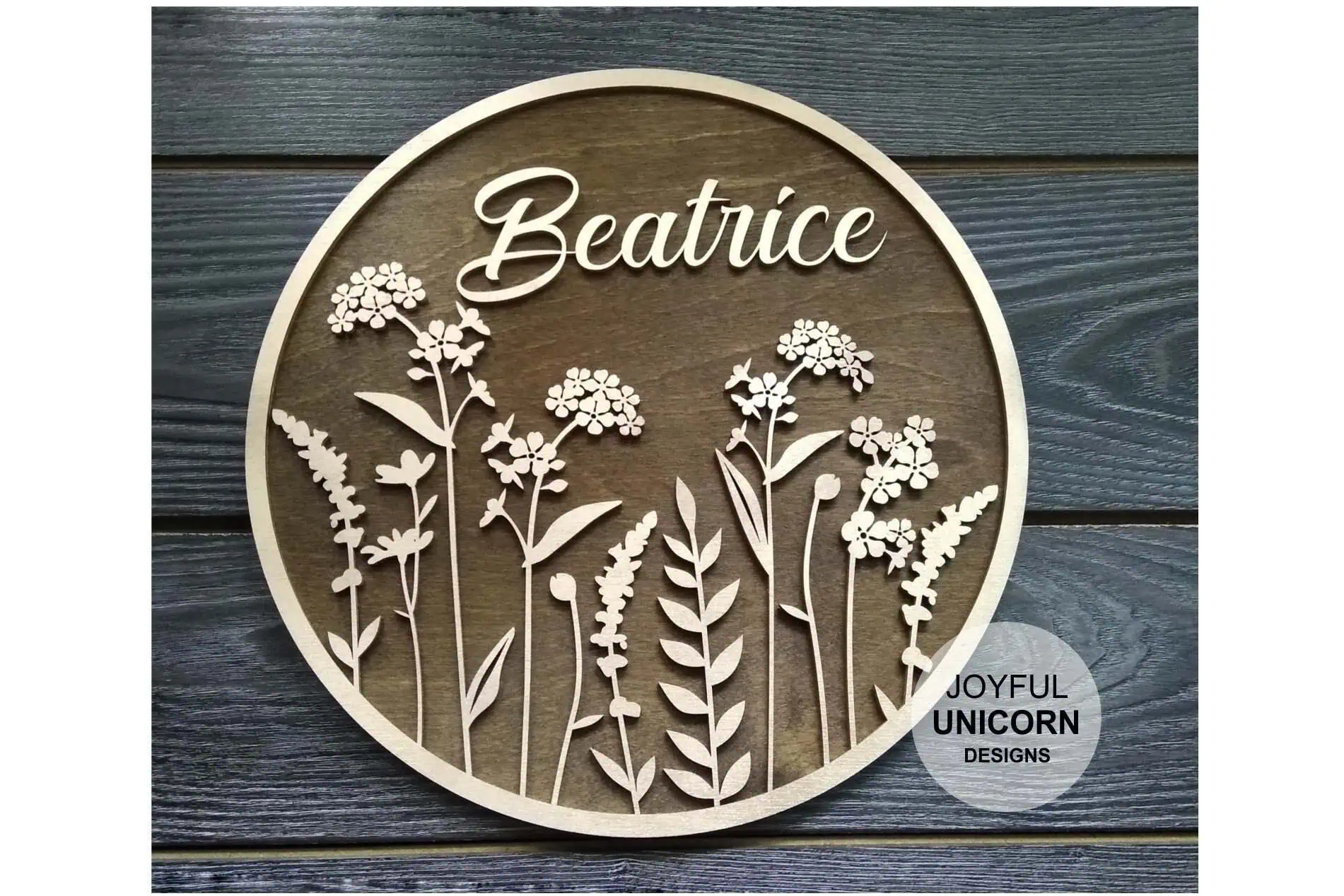 round layered wooden nursery sign with the name Beatrice in script above wildflowers