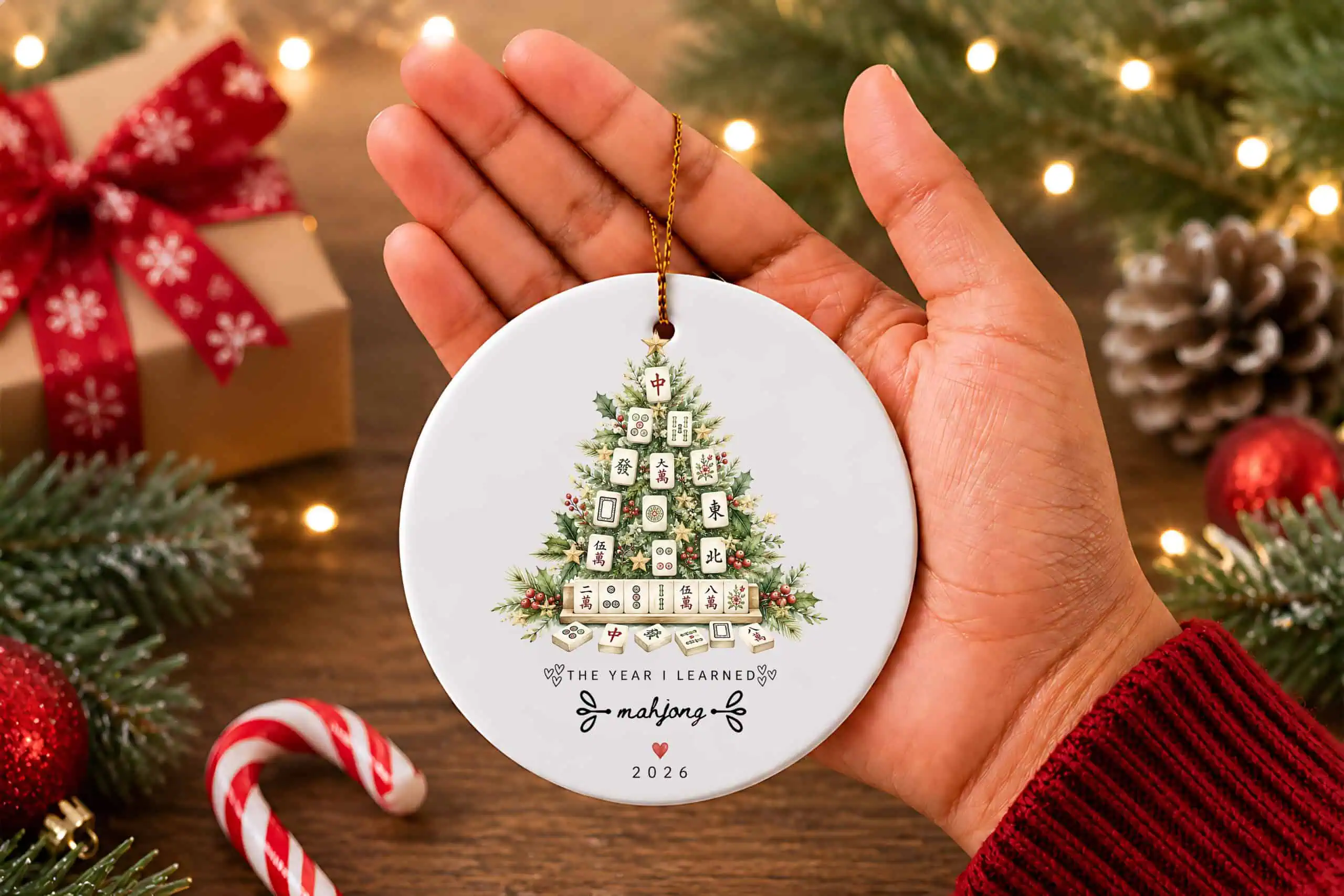 hand holding a white round ornament with a Christmas tree made of mahjong tiles and the words the year I learned mahjong 2026
