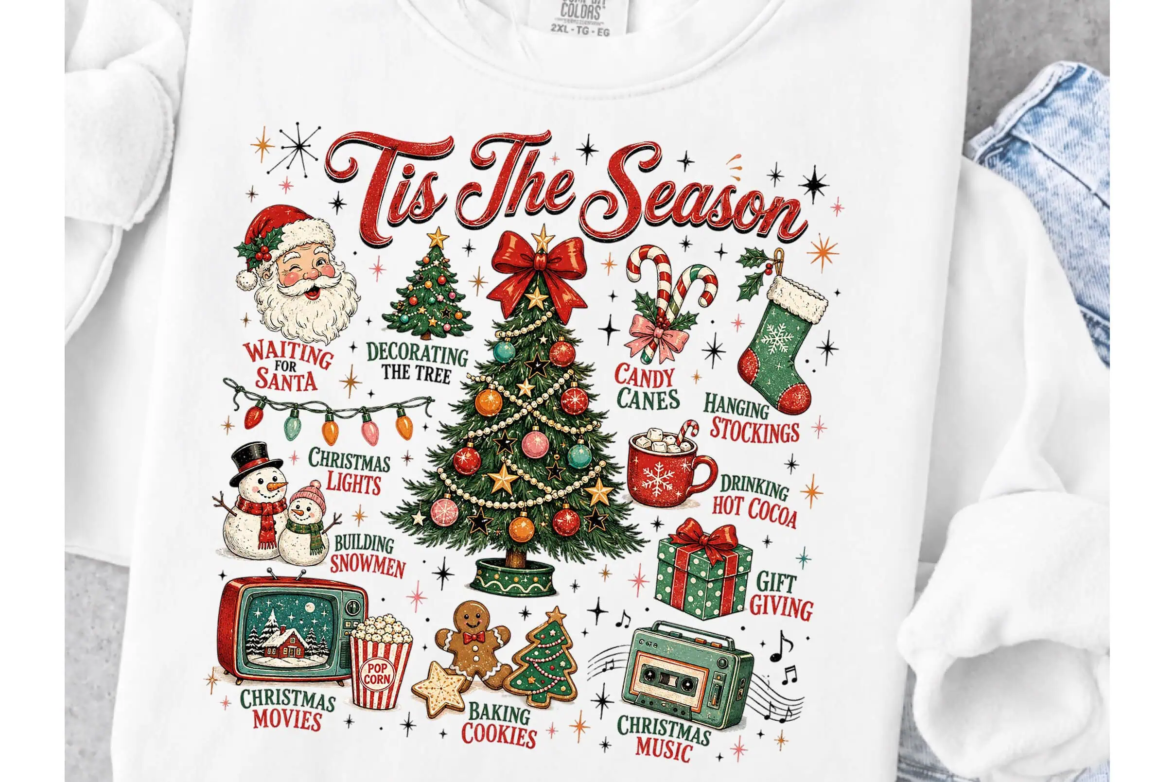 white sweatshirt that says Tis the Season with a retro Christmas tree, Santa, a snowman, presents and holiday activities