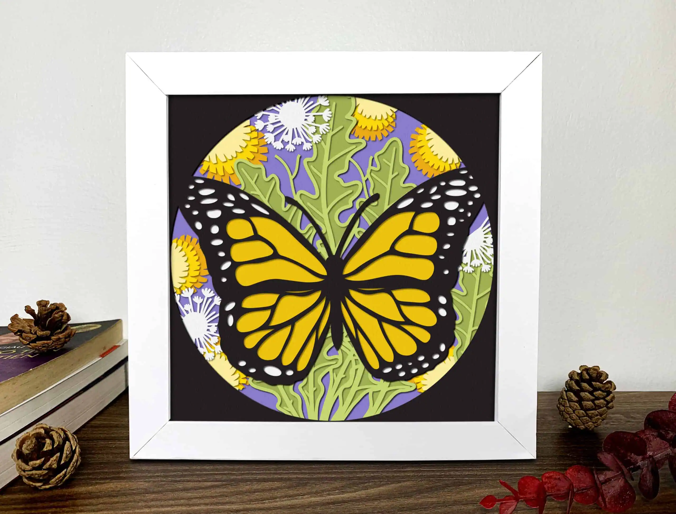 round layered shadow box with an orange monarch butterfly over yellow flowers in a white frame