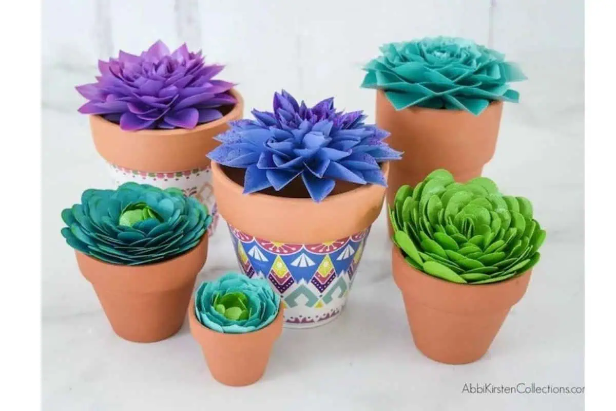 colorful paper succulents in purple, blue and green planted in terracotta pots