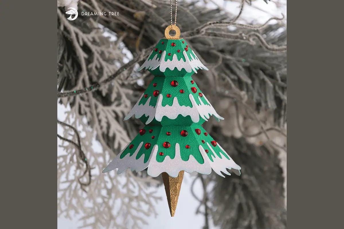 green layered paper Christmas tree ornament with snowy tips and red gems